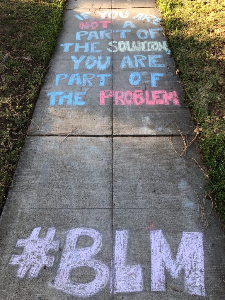 Chalk art reads "If you are not part of the solution you are part of the problem #BLM